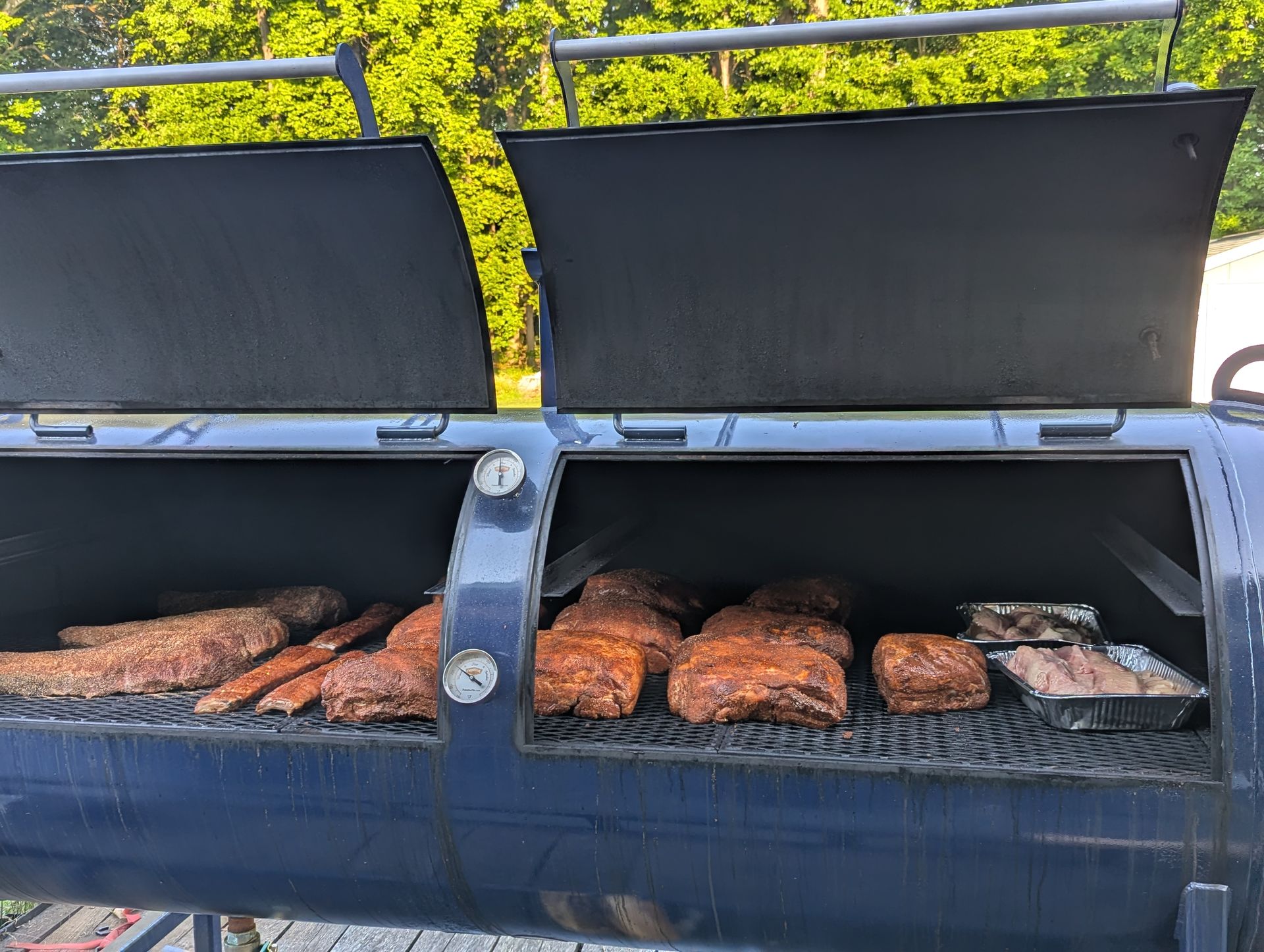 Both chambers of the 500-gallon Primitive Pits offset open — brisket, spare ribs, pork butts, and chicken on the grate