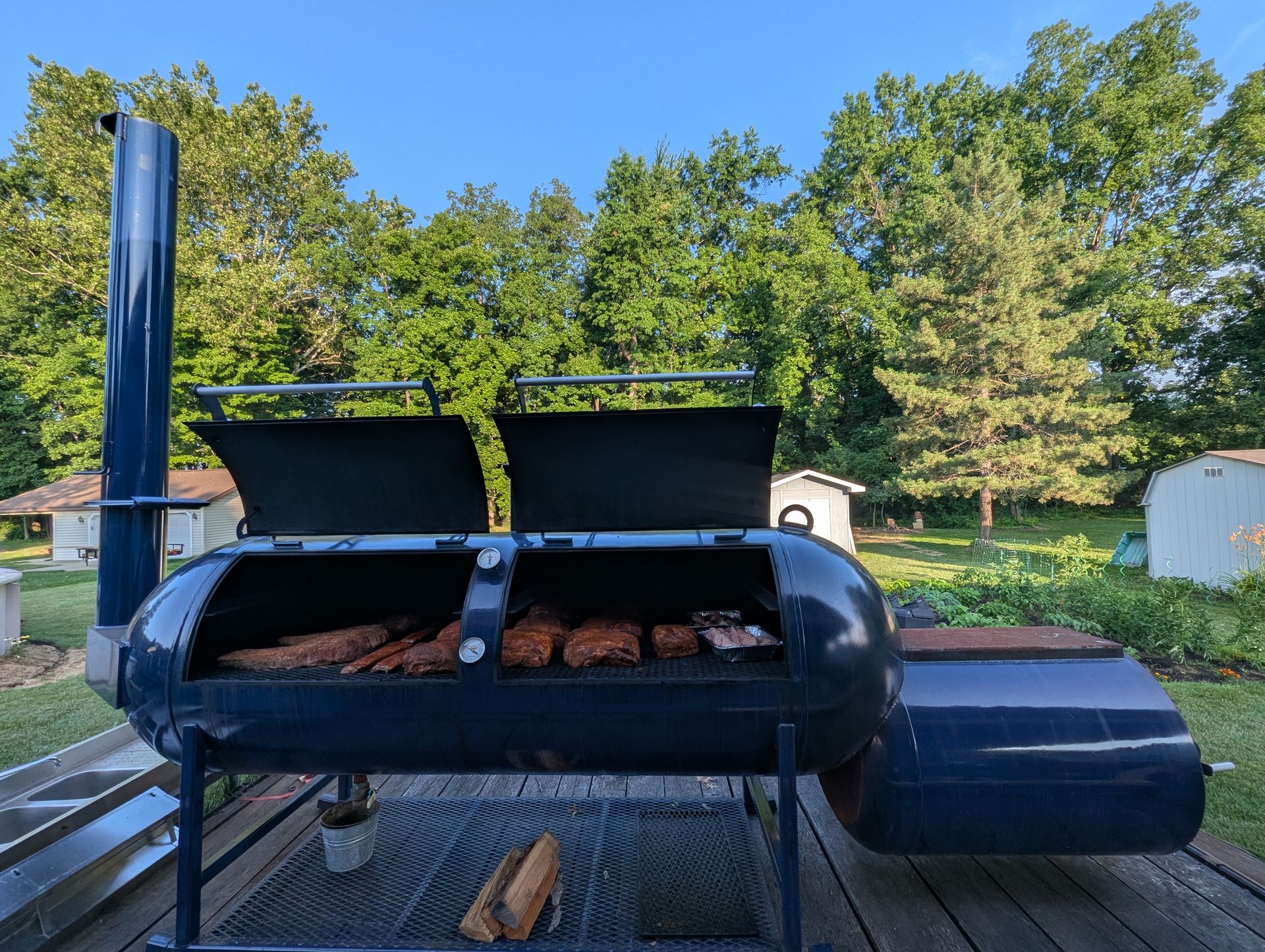 The navy 500-gallon Primitive Pits offset smoker on the deck in Amherst, Ohio, loaded for a cook
