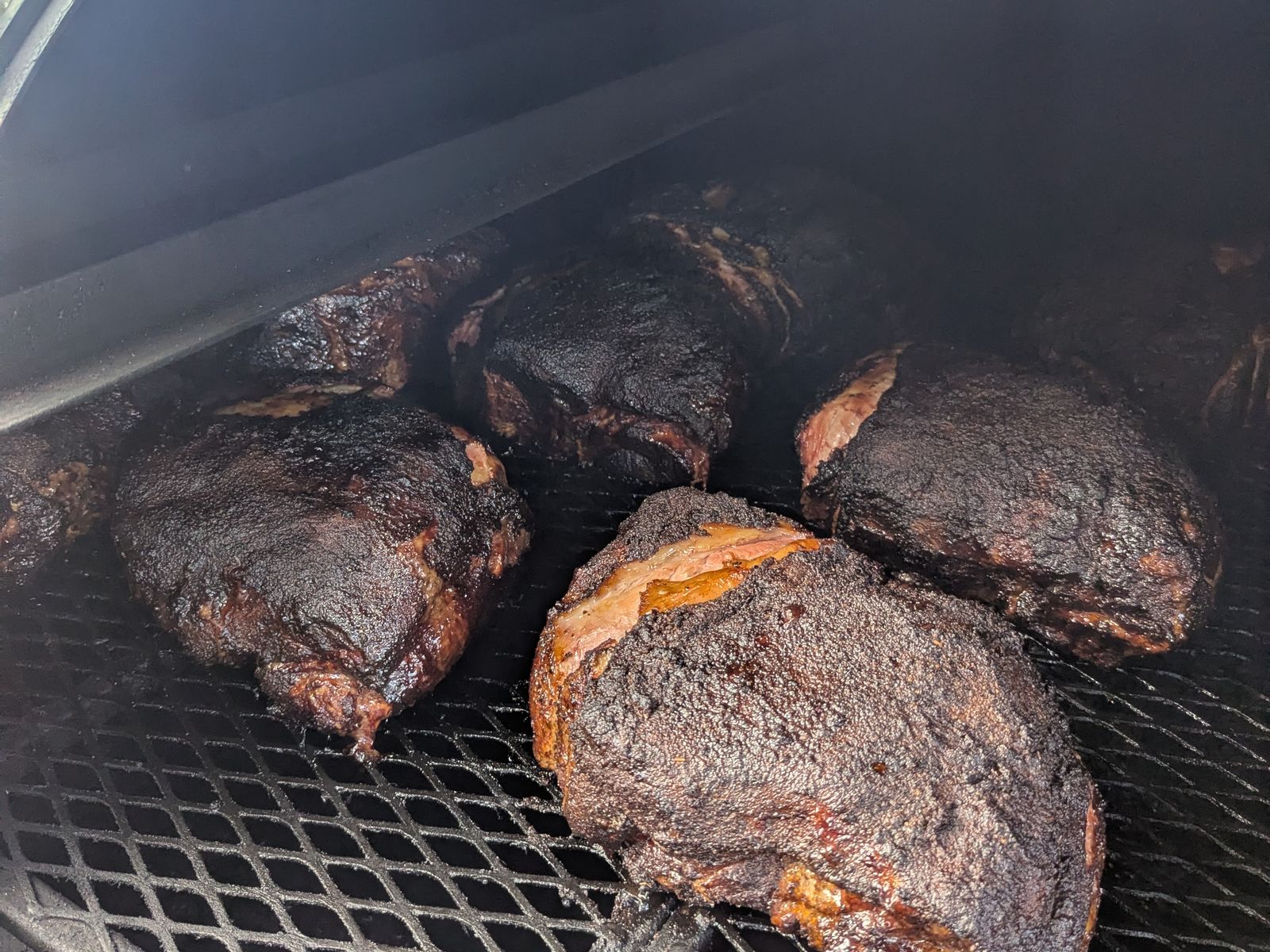 Dark-bark smoked pork butts near the end of the cook, smoke still rolling