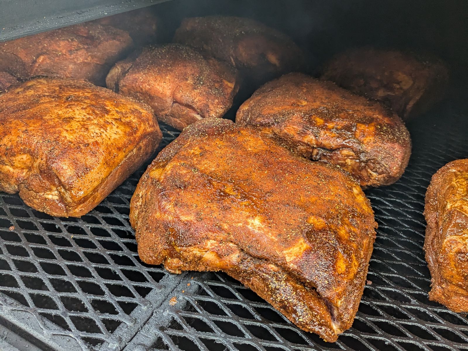 Pork shoulders taking on color over wood smoke